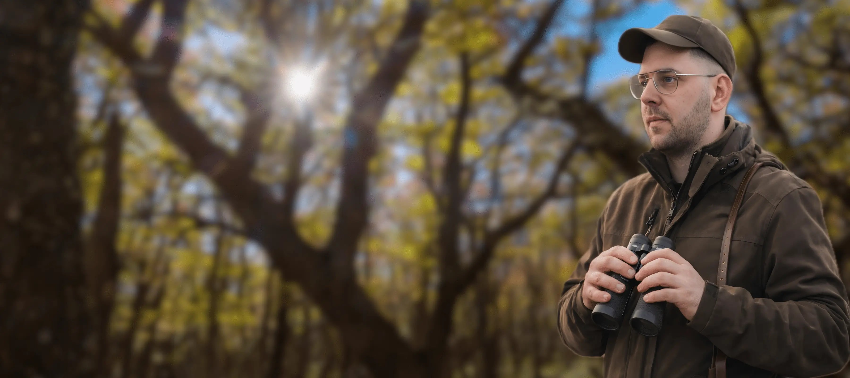 Dominic von Waidreich als Jaeger im Wald mit Fernglas als authentisches Portrait fuer Webdesign im Jagd- und Waffenumfeld