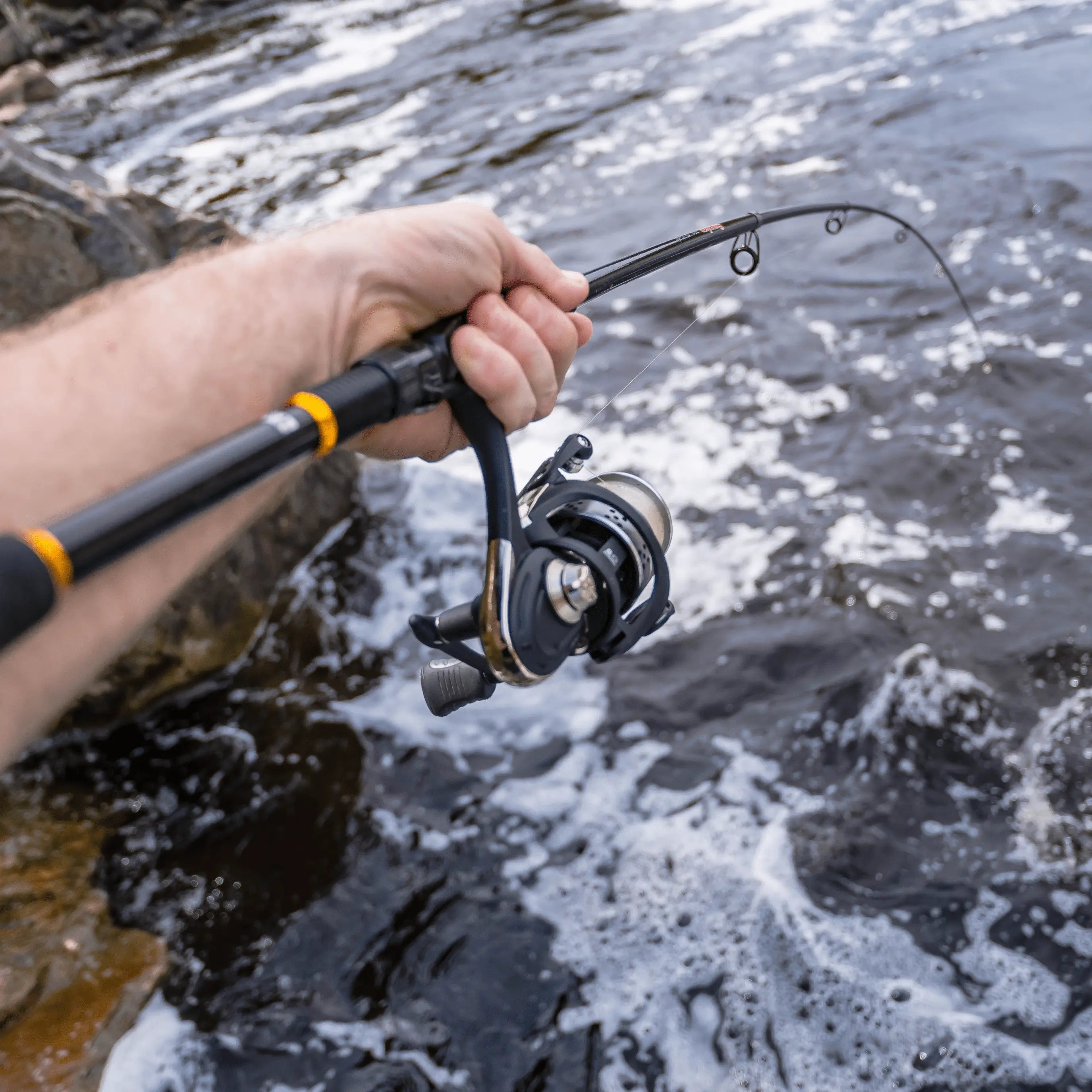 Hand mit Angelrute beim Spinnfischen im Fluss als persönlicher Moment aus Fischerei und Natur