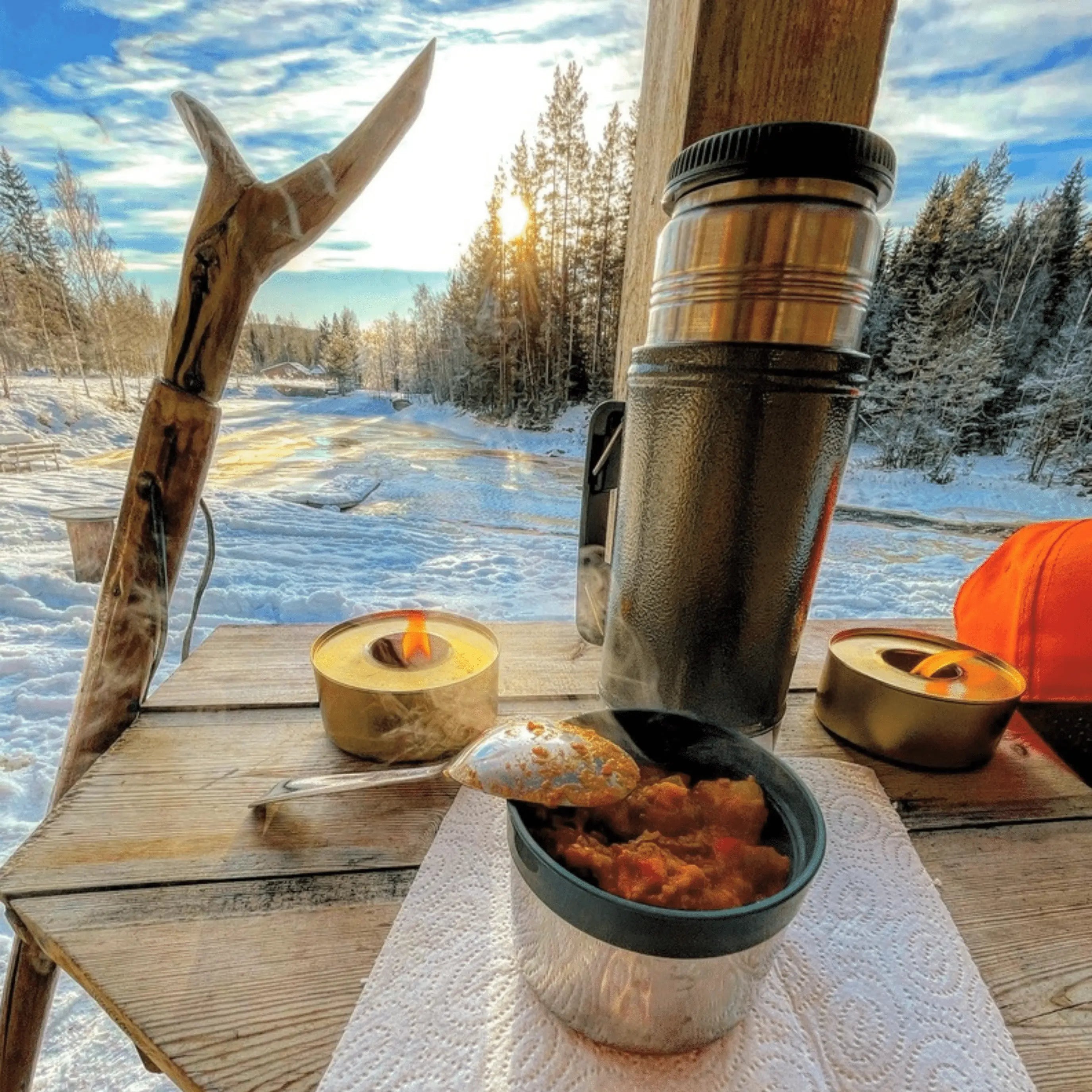 Warme Mahlzeit und Thermoskanne in winterlicher Natur als persönlicher Moment aus Outdoor und Ruhe